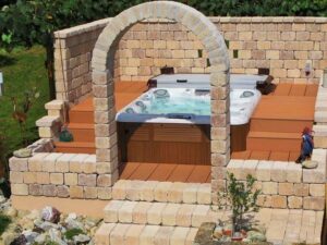 an inground hot tub on a deck, surrounded by stone walls for the hot tub enclosure